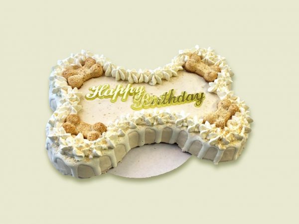 A large bone-shaped dog cake with white frosting, cream piped border, and biscuit decorations on top.