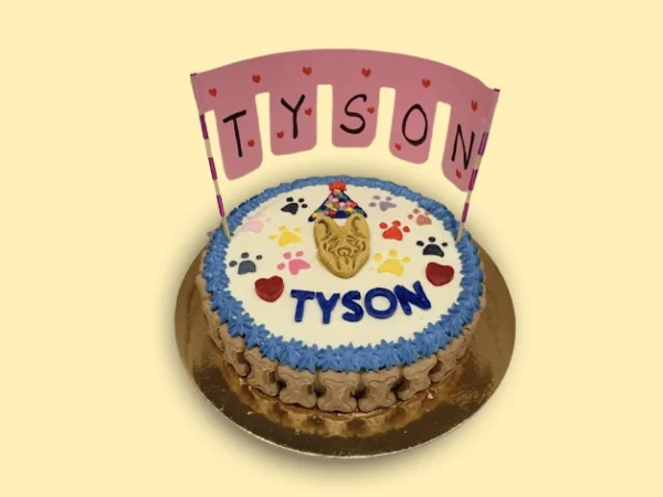 Round birthday cake with colorful frosting, decorated with bone-shaped biscuits